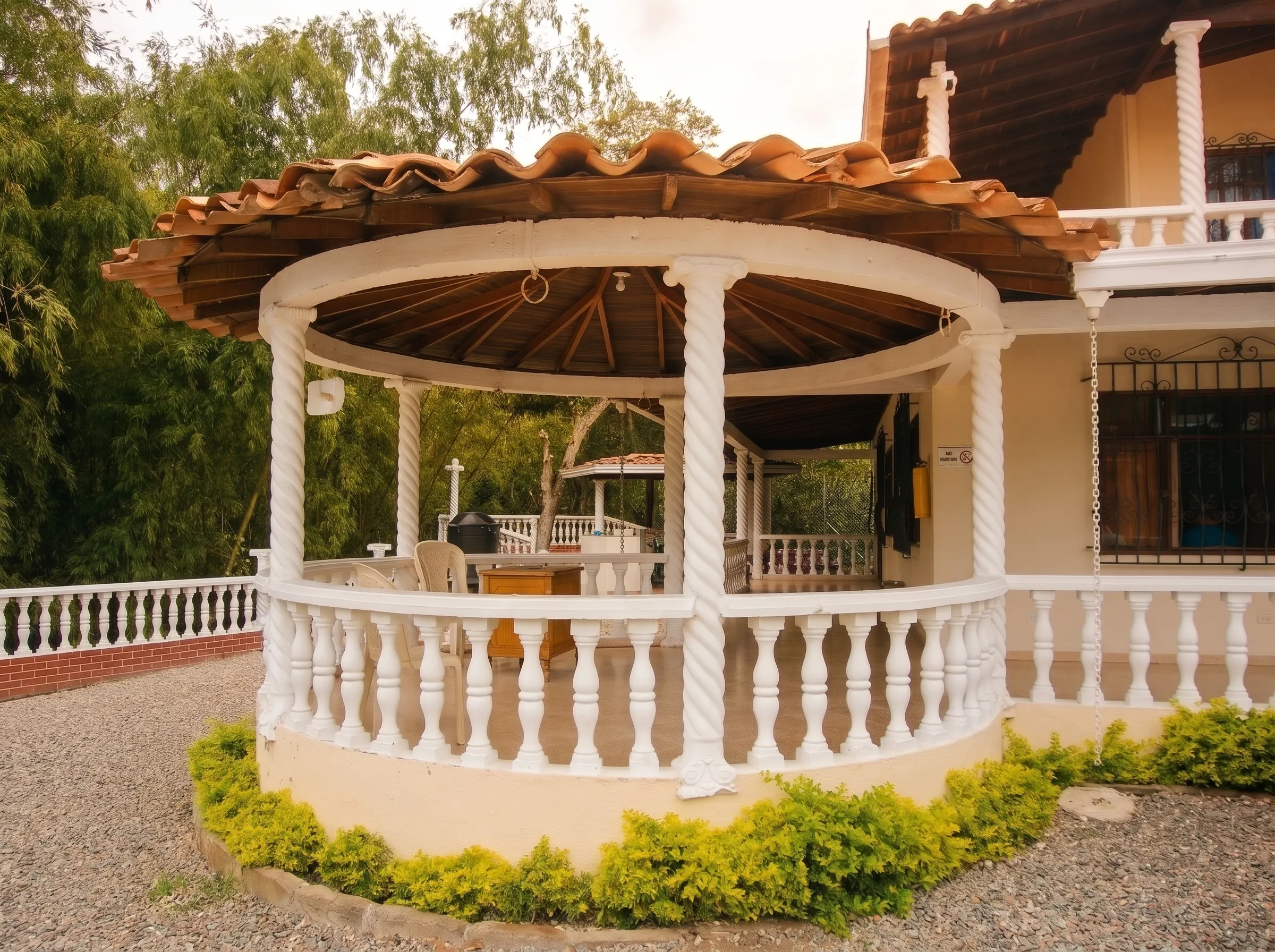 Kiosco circular con columnas blancas junto a la casa